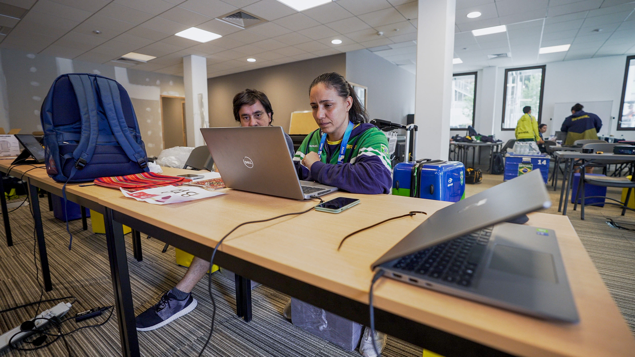 Daniela Polzin sentada em uma mesa com o computador na Vila Olímpica Paris 2024